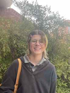 image of quinn smiling in front of a bush with flowers